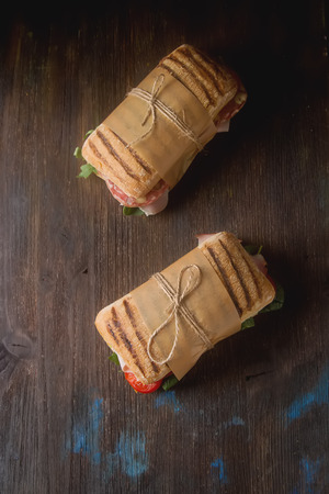 French baguette with sausage, tomatoes and lettuce. Dark backgroundの写真素材