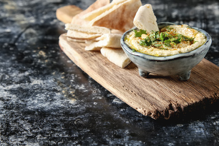 Classic hummus with herbs, olive oil in a vintage ceramic bowl and pita bread. Traditional Middle...