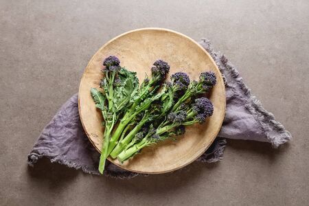Fresh purple broccoli on a wooden plate. Vegan food. Dark backgroundの写真素材