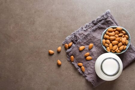 Dairy alternative milk. Almond milk in a glass bottle and fresh nuts over a gray background, selective focus. Clean eating, dairy-free, vegan, vegetarian, allergy-friendly, healthy food concept.の写真素材