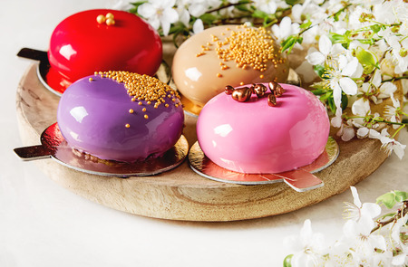 Fashionable mousse cake with a mirror glaze decorated with spring flowers. Light white backgroundの写真素材