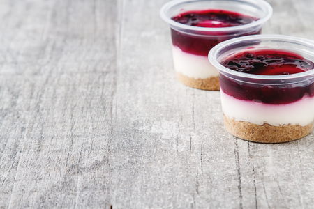 Ready berry cheesecake in a plastic pot. Dark gray wooden backgroundの写真素材