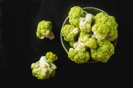 Ripe green cauliflower on a plate. Dark wood backgroundの写真素材