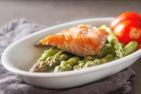 Fresh green asparagus on a white plate with salmon and tomatoes. Farmer's Market. Gray backgroundの写真素材