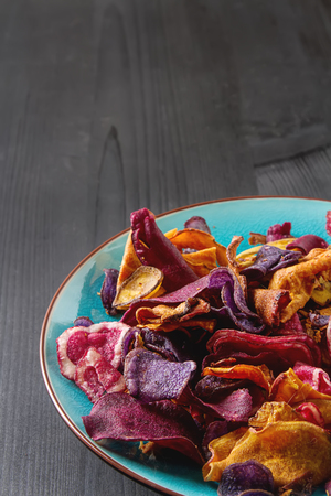 Beet and carrot salty chips in an old blue plate. wood backgroundの写真素材