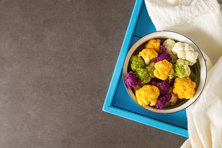 A rainbow of food. Purple cauliflower, orange cauliflower and broccoli, from the local market in London. Food for a vegan and a vegetarian. Dark backgroundの写真素材