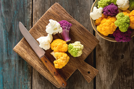 A rainbow of food. Purple cauliflower, orange cauliflower and broccoli, from the local market in London. Food for a vegan and a vegetarian. Dark backgroundの写真素材