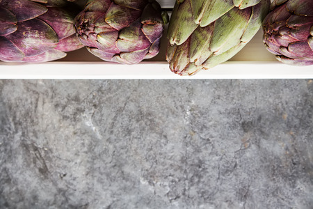 Baby ripping organic Artichokes with lemon. Food for a vegan and a vegetarian. Diet, food concept. Dark backgroundの写真素材