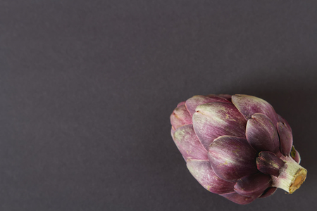 Baby ripping organic Artichokes with lemon. Food for a vegan and a vegetarian. Diet, food concept. Dark backgroundの写真素材