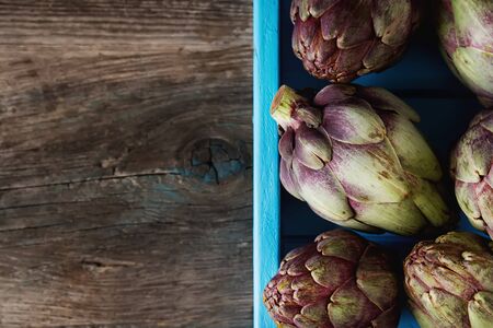 Baby ripping organic Artichokes with lemon. Food for a vegan and a vegetarian. Diet, food concept. Dark backgroundの写真素材