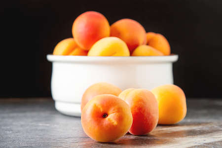 Ripe apricots in a bowl. Dark background. Food for a vegan and a vegetarian. Diet, detox, food conceptの写真素材