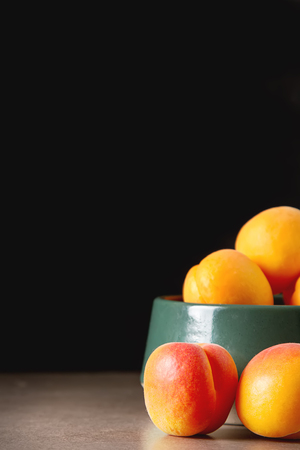Ripe apricots in a bowl. Dark background. Food for a vegan and a vegetarian. Diet, detox, food conceptの写真素材