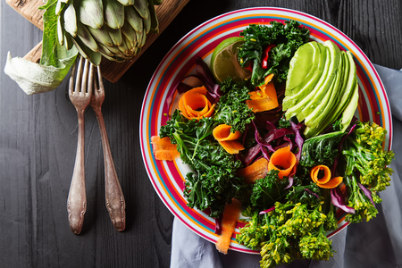 Fresh vegetarian salad with cabbage kale broccoli carrot egg avocado and artichokes on a white plate, napkin. Dark wood backgroundの写真素材