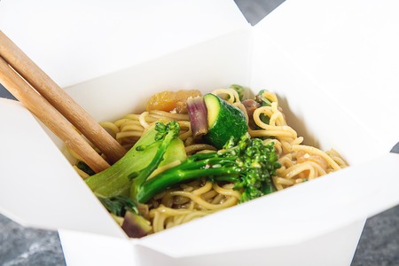 Chinese noodles with vegetables. Melon, onion, beans, broccoli. Food in the wok. Fast food. Dark backgroundの写真素材