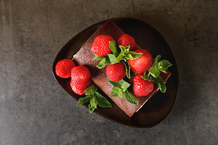 Delicious homemade chocolate cake with strawberries and mint. Dark background. Celebratory dinnerの写真素材
