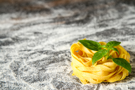 Homemade italian tagliatelle with flour and basil. Dark backgroundの写真素材