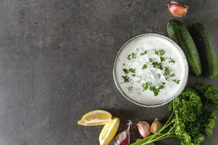 Sauce Tsatsiki with ingredients of cucumbers, garlic, parsley, lemon. Dark backgroundの写真素材