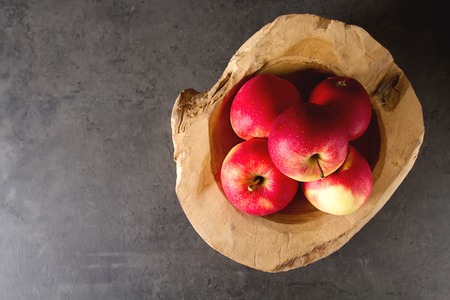 Ripe juicy apple in a wooden bowl. Dark background. Space for text