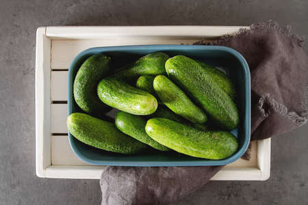 Fresh cucumbers in a blue bowl. Dark background. Healthy food, a delicious dietの写真素材