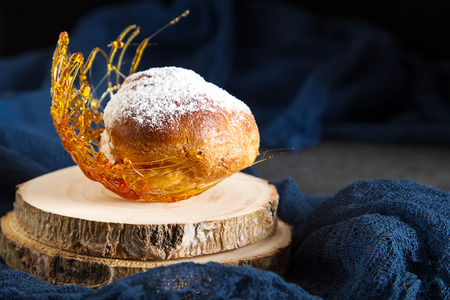 Italian dessert is profiterole with cream and caramel decoration. Dark backgroundの写真素材