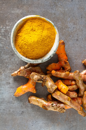 Turmeric powder and fresh turmeric. Dark background. Space for textの写真素材