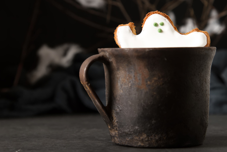Sweet Halloween. Hot cocoa with cookies in the form of ghosts, leaves and pumpkins. Dark background. Space for textの写真素材