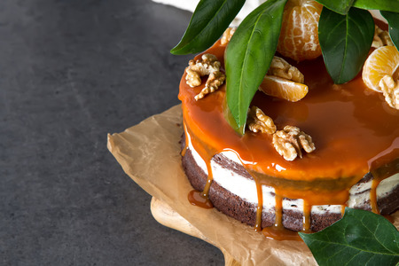 Chocolate cake with white cream and caramel sauce. Dark background. Birthday