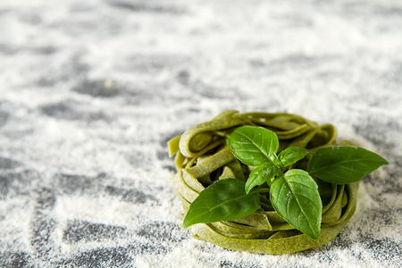 Homemade italian tagliatelle with flour and basil. Dark backgroundの写真素材