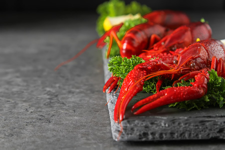 Delicious boiled crayfish close-up with lemon and parsley. Dark background. Dinner with seafoodの写真素材