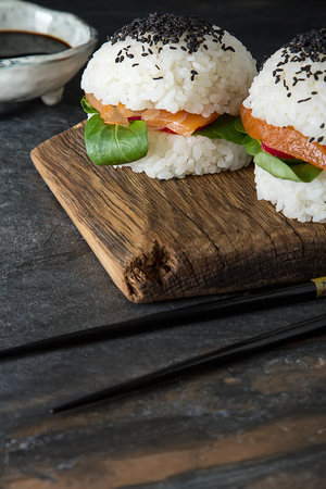 Rice sushi-burgers with smoked salmon, green salad and soy sauce. Modern healthy food. Dark backgroundの写真素材