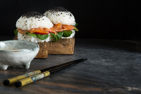 Rice sushi-burgers with smoked salmon, green salad and soy sauce. Modern healthy food. Dark backgroundの写真素材