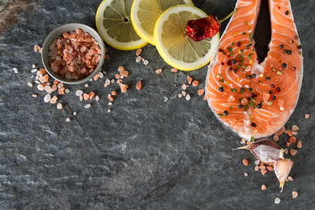 Salmon steak with lemon, and spices. Fresh fish. Dark backgroundの写真素材