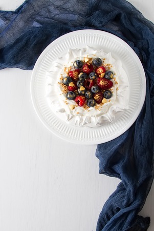 Pavlov's dessert with delicate cream and fresh berries of raspberries and blueberries. Light backgroundの写真素材