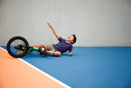 A boy kid fell of his bike in a park outdoorsの写真素材