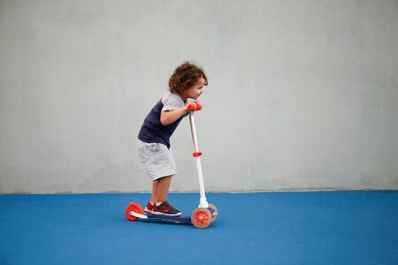 a child riding a scooter outdoors not wearing a protectionの写真素材