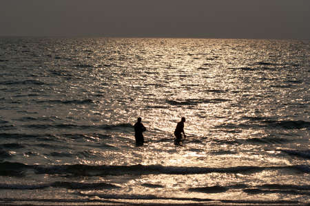 Silhouette of men in the sea at a beach.の写真素材
