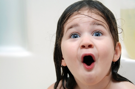 Little girl reacts to bathtime   Her mouth is open in amazement and her hair is soaking wet の写真素材