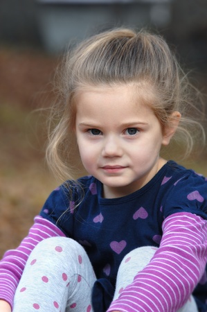 Adorable little girl sits serene and still   Her face expresses a thoughtful and contemplative look as she enjoys the outdoors の写真素材