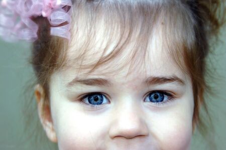 Extreme closeup of little girl's face.  She has blue eyes and a twinkle.の写真素材