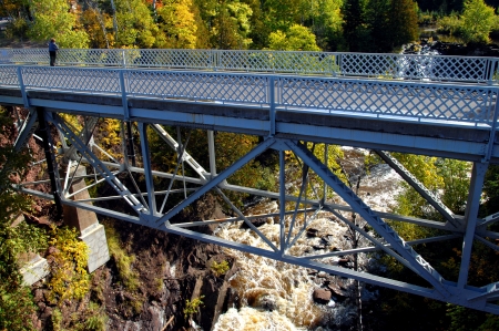Eagle River Falls is observed by a woman standing on the Eagle River Bridge in Upper Peninsula, Michigan   Autumn colors hillside and gorge の写真素材
