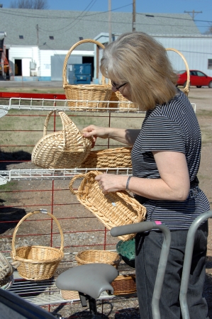 Garage saler, hunts through rack of wicker and ratan baskets for a bargain の写真素材