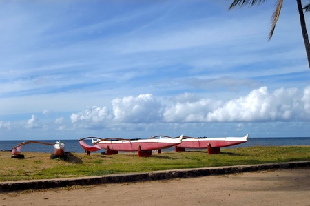 Outrigger canoes sit on northern shore of the island of Oahua.  Each rests on tire prop framed by ocean and clouds.の写真素材