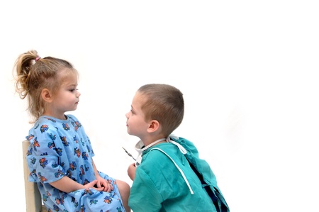 Two little children play doctor.  The little girl is the patient and the little boy is the physician.  He is holding an instrument and beginning the examination.の写真素材
