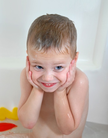Little boy holds his hands over his ears.  He dreads the ritual cleaning every evening after playing outdoors.の写真素材