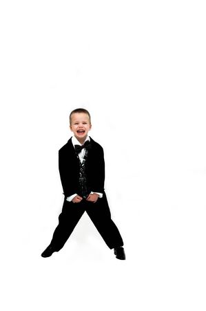 Little boy in tuxedo laughs hilariously   He is standing with feet spread holding the ends of his silver and black tuxedo vest の写真素材