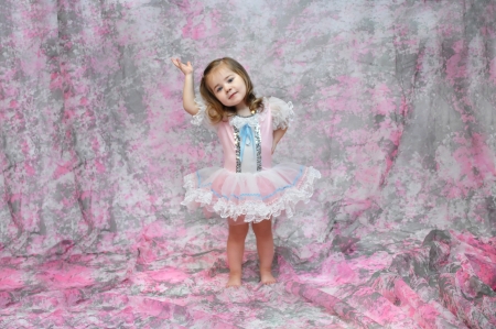 Baby ballerina shows off her ballet moves   She is dressed in a pink, blue and white tutu   She has her arm raised and the other on her hip の写真素材