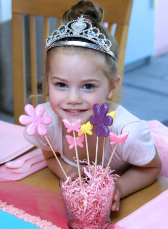 Little girl has ballerina birthday party   She poses besides her decorations wearing aa crown and tutu の写真素材