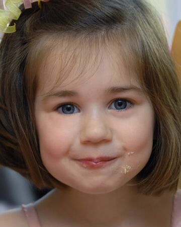 Little girl pigs out on birthday cake at a party   She is  enjoying her cake and eating it too  の写真素材