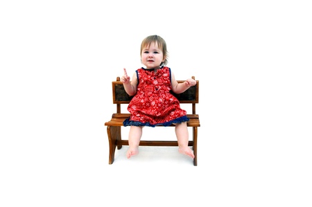 Little baby girl holds a single finger up to illustrate how old she is   Then frowns in confusion   She is wearing a red paisley print dress and is barefoot   All white room の写真素材