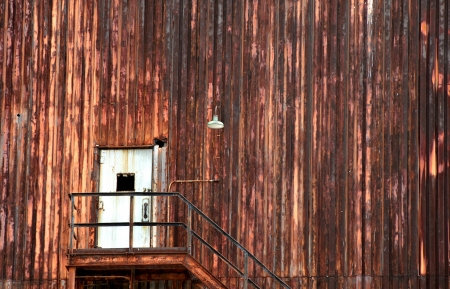 Background image shows industrial building rusty and abandoned.  Doorway has broken window and rusted stairway.の写真素材